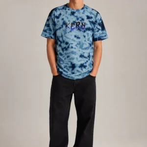 Full-body model wearing KERN Graphic Ocean Blue Tie-Dye Tee with black wide-leg trousers and white sneakers on a light studio background.